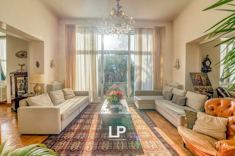 living room, chandelier, white sofas, coffee table, large windows, carpet, wall decorations