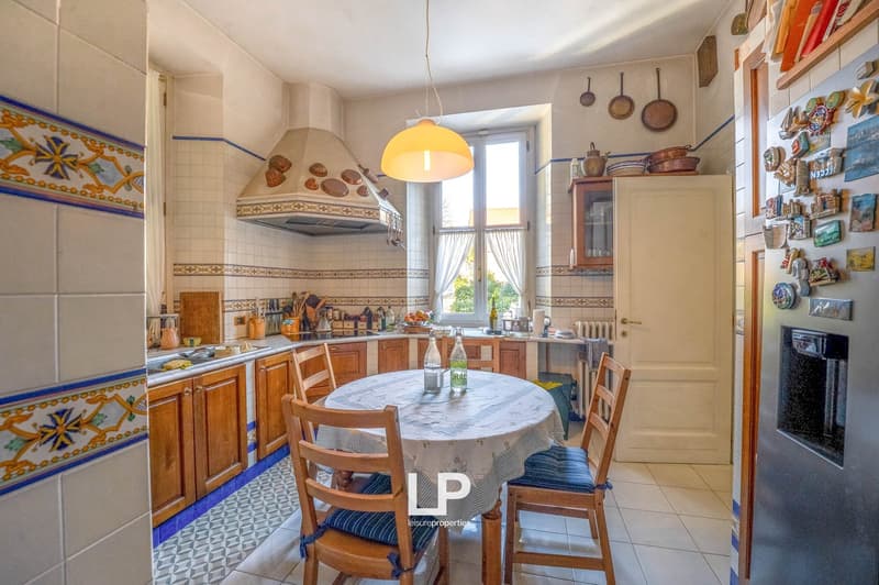 kitchen with dining table, chairs, sink, cooking utensils, wooden cabinets, table lamp, fridge, tiled walls and floor