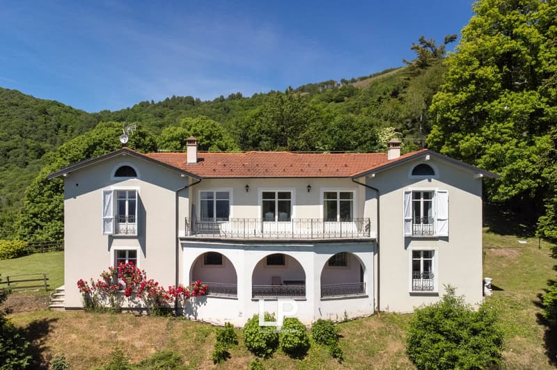 2-story house, white exterior, red roof, arched windows, multiple balconies, stairs, surrounded by greenery, chimneys
