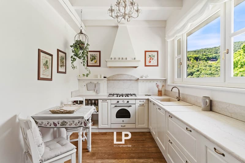white kitchen, oven, stove, sink, large window, chandelier, kitchen island, wooden floor