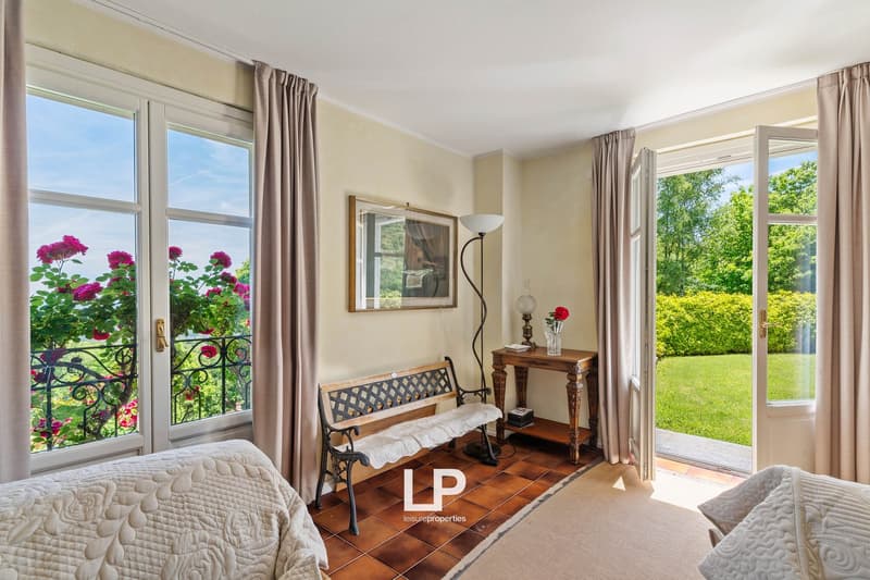 2 couches, wooden bench, table with lamp and vase, picture frame, double doors, windows, tiles