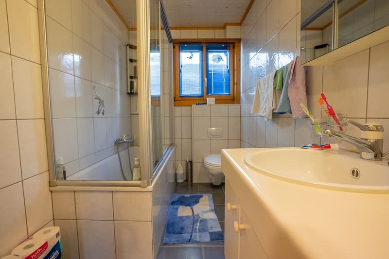 Bathroom: bathtub, toilet, sink, mirror, towels, toiletries, tiled walls, window, shower curtain