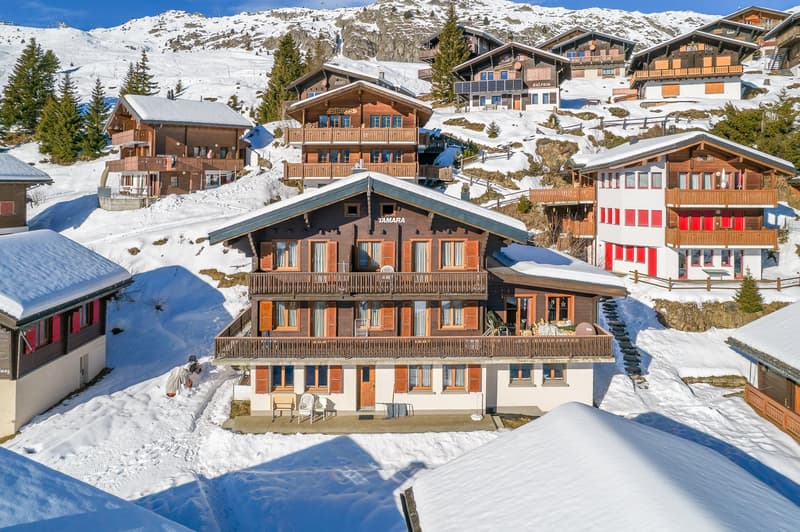 Mountain chalet, wooden exterior, multiple levels, balconies, snow-covered surroundings