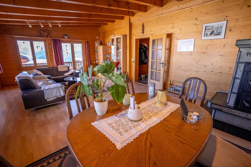 wooden floors, wooden walls, wooden ceiling, fireplace, dining table, chairs, sofa, center table, potted plant, picture frames, glass windows