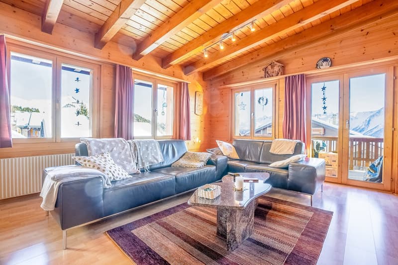 two sofas, wooden beams ceiling, wooden floor, double doors to terrace, large windows, rug, coffee table, fireplace