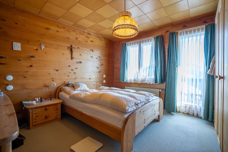 wooden bed, pillows, nightstand, window, radiator
