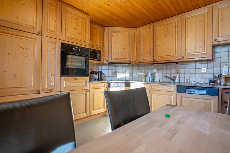 large wooden cabinets, tiled floor, white countertops, sink, stove, oven, coffee maker, dishwasher, kitchen table, chairs