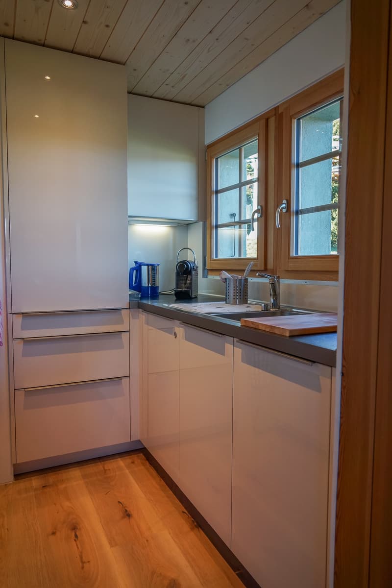white cabinets, wooden floor, double stainless steel sink, window