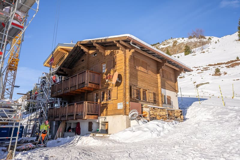 wooden 2 story house, several balconies, snowy mountain in the background
