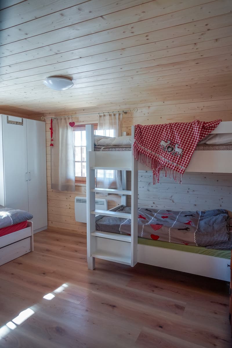 Room with wooden walls, bunk beds, cabinets, and radiator