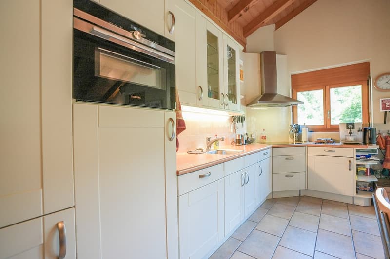 White cabinets, stainless steel sink, dishwasher, oven, stove, microwave, window, tiled floor, kitchen accessories