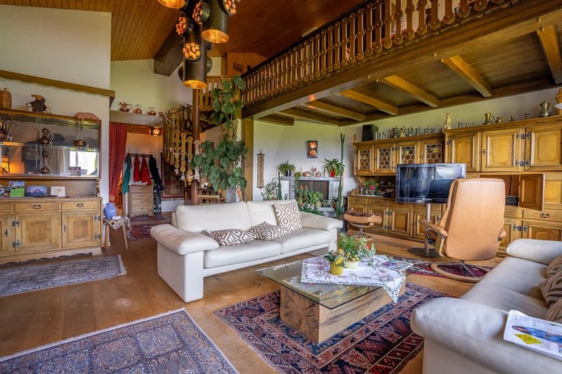 Spacious room with white sofas, wooden coffee table, carpeted floor, wooden cabinet, TV, staircase