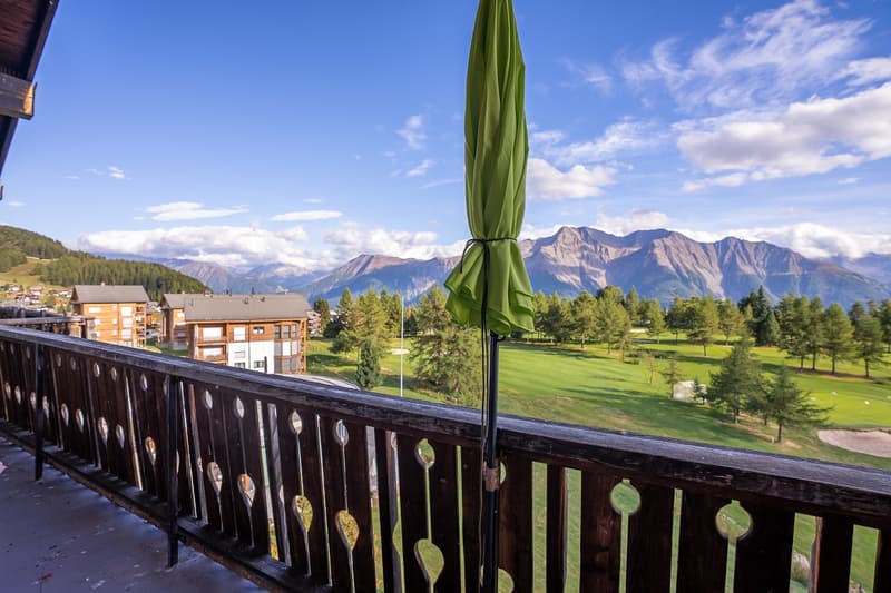 a view of a mountain with a golf course from a balcony