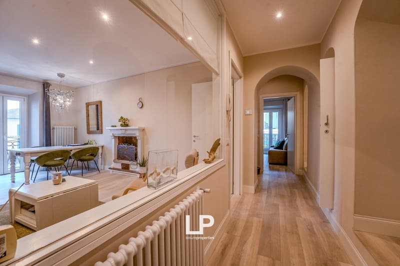 Chandelier, fireplace, wooden floor, dining table with chairs, couch, coffee table, mirror, radiator