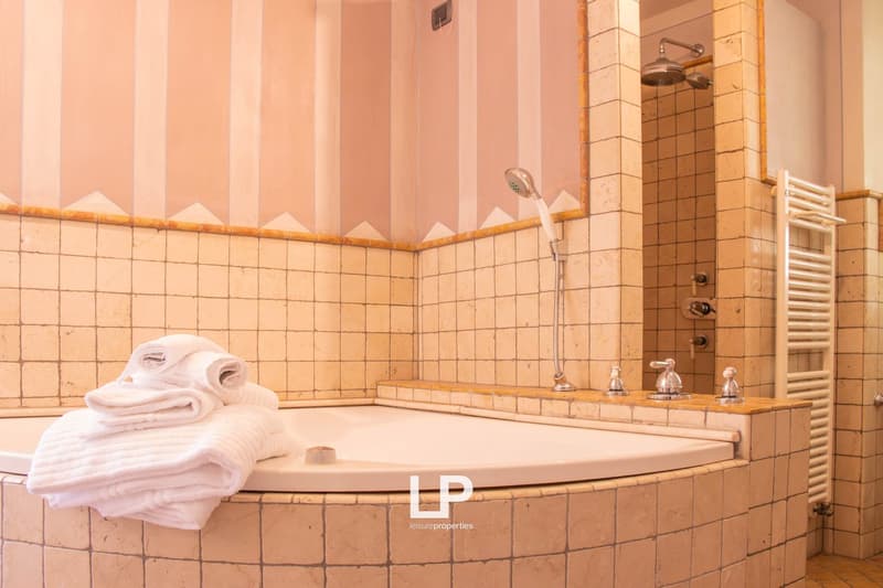 large bathtub, tiled walls, modern shower with tiled wall, white towels