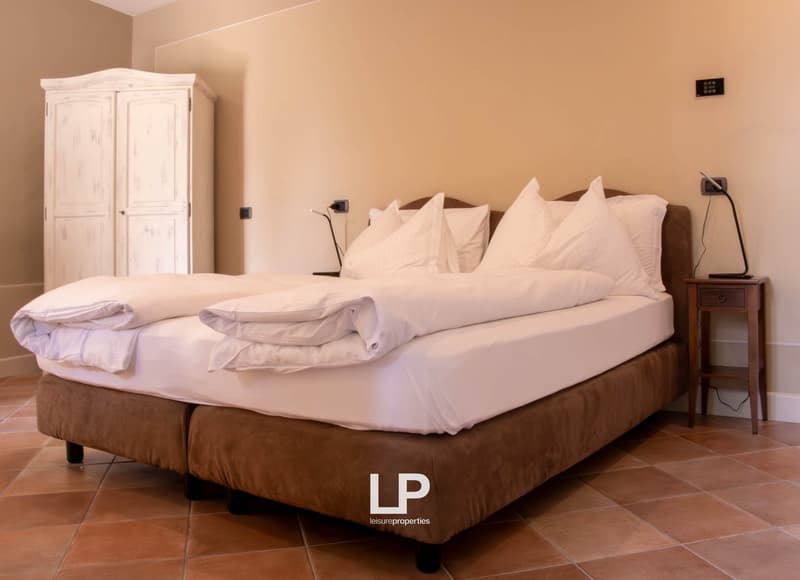 double bed with white sheets and pillows, wooden night tables, white wardrobe, tiled floor