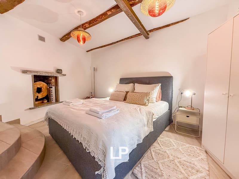 exposed beams, fireplace, queen-size bed, nightstand, floor lamp, white wall, carpet
