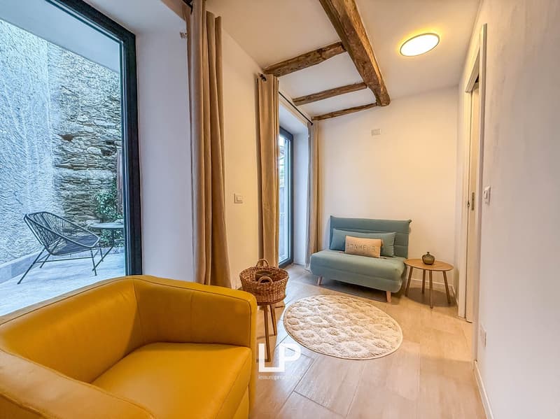 Large window with terrace, wooden flooring, yellow chair, round rug, beige loveseat, table, and decorative bowl