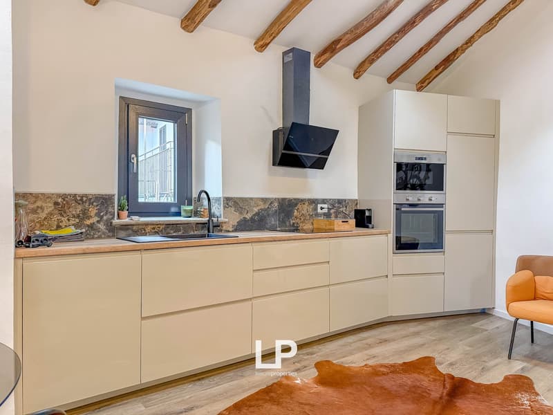 kitchen, wooden floor, wooden beams, white cabinets, granite countertop, stainless steel appliances, window with balcony, double oven