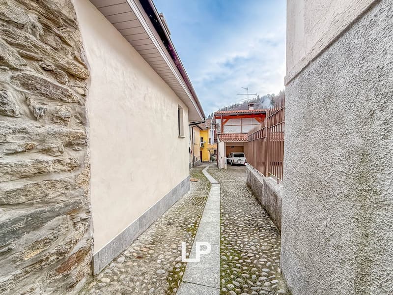 cobblestone street, stone walls, white walls, brown fence, cars in the distance