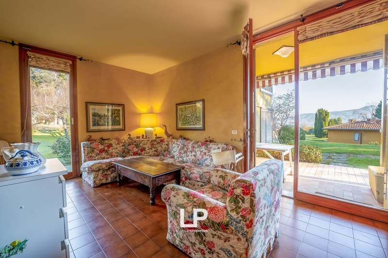 wooden coffee table, floral sofa, lamp, framed pictures on wall, tiled floor, balcony