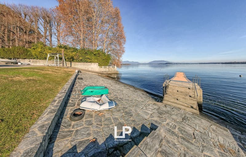 stony shore with grass lawn, waterside, two boats on the shore, mountain landscape