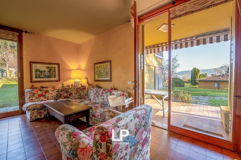 large floral sofa, wooden coffee table, large glass door to the terrace, picture frames, lamps, chairs