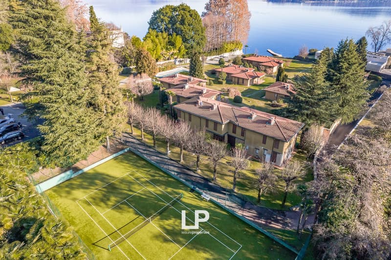 Tennis court with green field and surrounding green landscape with lake view