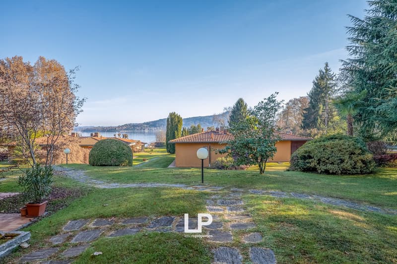 lawn, various shrubs, trees, stone path, distant water, distant buildings