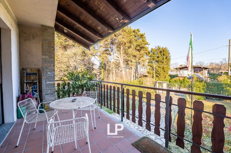 balcony with a table and chairs, surrounded by wooden railing, small garden with plants, outdoor view