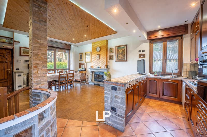 kitchen with dining area, wooden floors, white walls, fireplace, breakfast nook, dining table and chairs, large windows, wood shelves, wooden pillar