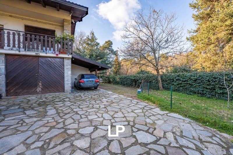 Detached house with brown wooden garage doors and stone-paved driveway.