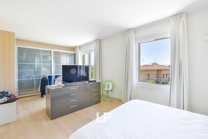 bedroom with large windows, bed, chair, television, large closet, wooden floor