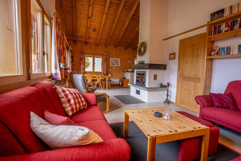 Fireplace, wooden beam ceiling, red sofa, wooden table, carpet, chairs