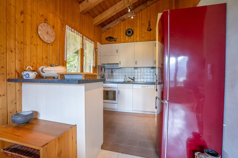 kitchen with white cabinets, wooden counter, tiled floor, red fridge, dishwasher, stove, wooden decorative elements on the wall, wall clock, basket on the floor, teapot, bowl, tray