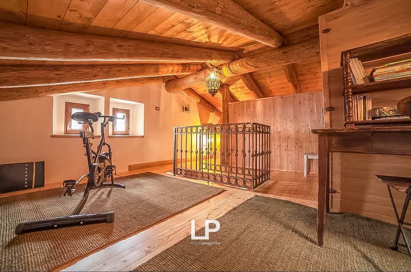 wooden beam ceiling, exercise bike, iron railing, wooden desk, books shelf