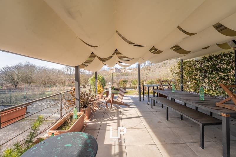 covered outdoor dining area with table, benches, chairs, plants