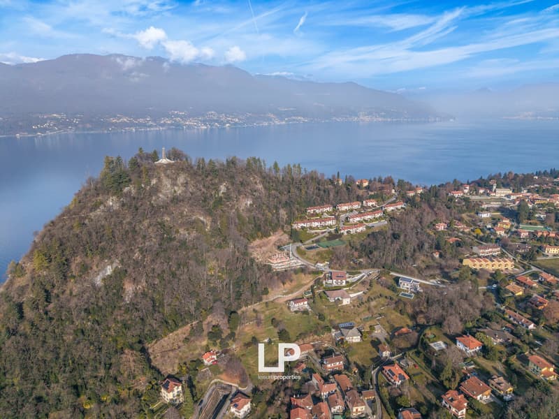 Hillside property with lake and mountain views, multiple houses, solar panels, trees, roads