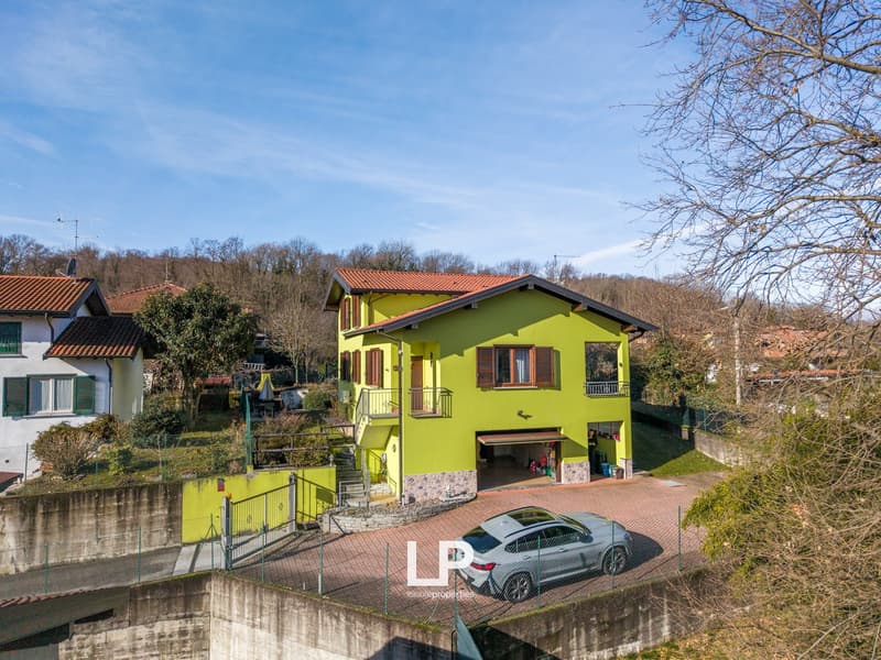 Detached house with garage, surrounded by trees and other houses