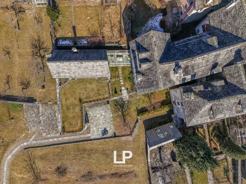 Two-story building, stone exterior, balcony, garden, driveway
