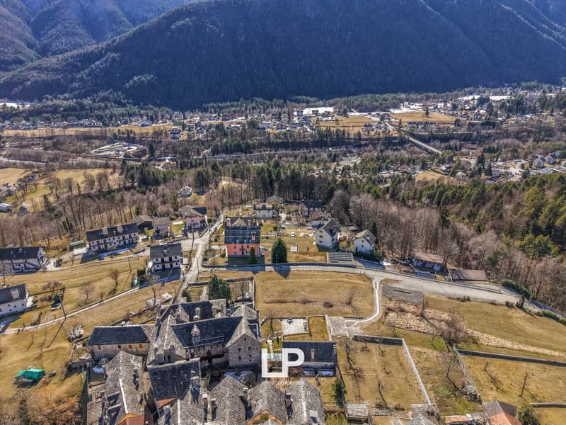 Cluster of buildings in a rural area, stone-built houses with slate roofs, open field in front