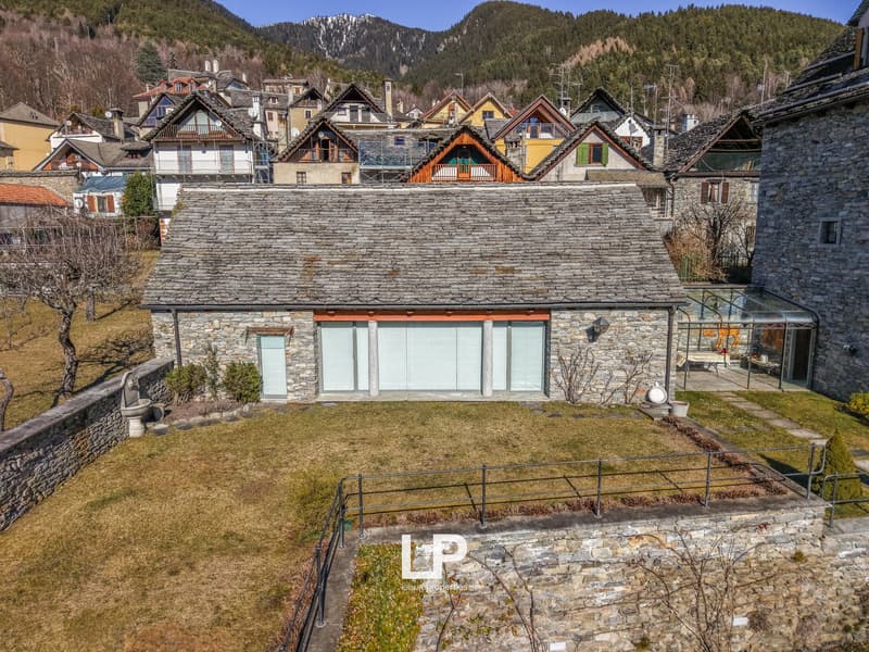 Detached house with garage, stone walls, roof terrace, large windows, mountains in the background