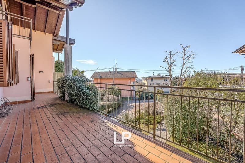 Terrace with brick flooring, metal railing, wooden beams, small seating area