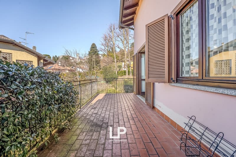 Balcony with brick flooring and wrought iron railing, closed windows with shutters