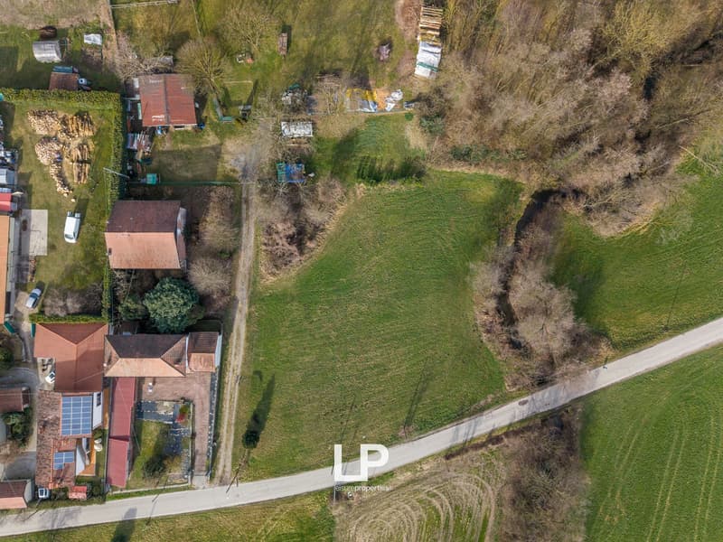 Aerial view of a rural area with several houses, a large field, and a road.