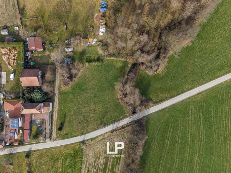House with solar panels, surrounded by fields, driveway, and a road