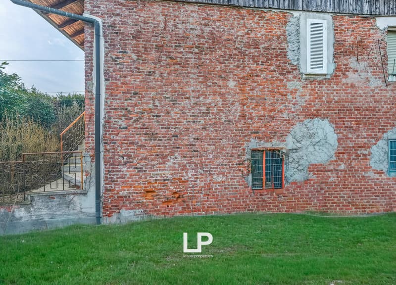 Old brick building, metal railings, small window, green grass, metal pipe