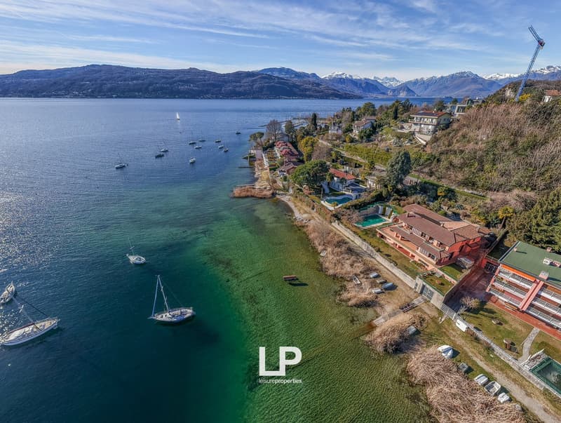 Aerial view of a lake with boats, mountains, and houses on the shore