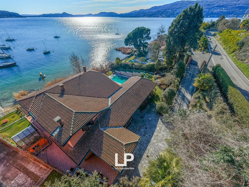 House with brown roof, swimming pool, lake view, surrounded by trees and plants