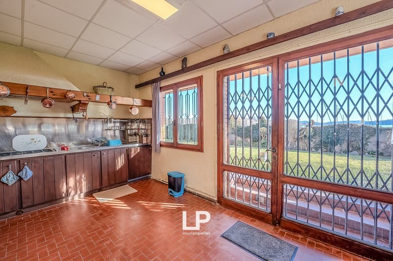 kitchen with wooden cabinets, tiled floor, large windows, view of the garden